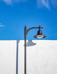 Lantern in sunlight and shadow on white wall