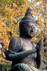 Statue of Buddha against trees with yellow leaves in Tokyo