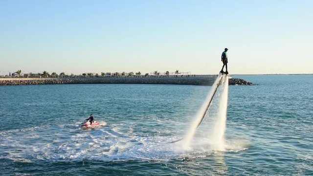 Fly boarding with jet ski extreme water sports in Ras al Khaimah, United Arab Emirates near Dubai at sunset having fun on the water. Recreation and sports concepts.	