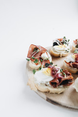Delicious fresh bruschettas with eggs, salmon, olives and meat , traditional Italian cuisine, ingredients on white table 