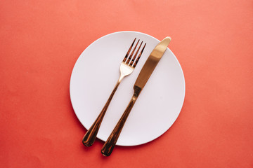 white plate, fork, knife on red table, elegant tableware 