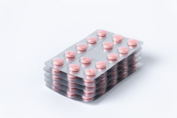 Pink medical pills in silver blister packs. On white background. 