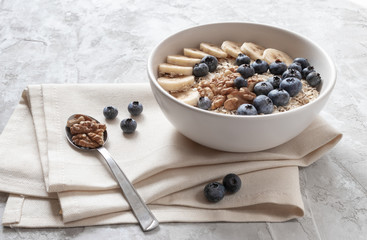 Healthy breakfast. Oatmeal with sliced banana, blueberry and walnut on the linen towel for tasty breakfast