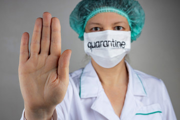 A doctor in a medical mask with the inscription quarantine shows a stop sign with his palm on the COVID 19 epidemic, close-up, shallow depth of field, selective focus. The concept of quarantine