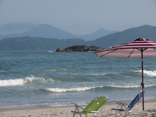 Empty beach and umbrella with no people on the sand and empty chairs