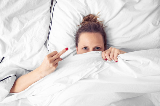 Frau in Bett mit Mittelfinder "Fuck you"