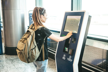 Girl tourist or student buys a ticket for transport in the self-service terminal