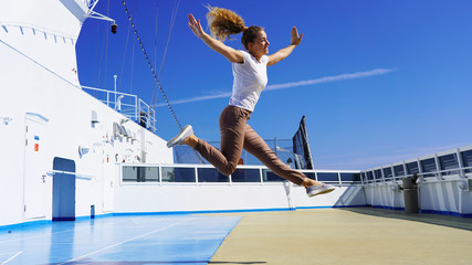 Fototapeta na wymiar Rock sign performed by a curly curly girl. beautiful sporty girl on the deck of a cruise ship jumps Sign of the horns. Emotion fun joy on a sunny day. rest on a cruise ship. vacation