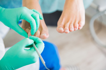 Woman sitting in chair, having foot treatment in spa salon.  Professional medical pedicure...