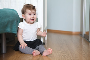 Baby girl sitting on the floor in room, smiling and happy Caucasian child
