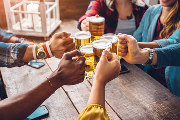 Group of people enjoying and toasting a beer in brewery pub - Friendship concept with young people...