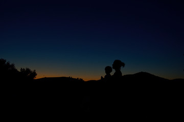 Silhouettes of mother and son at night