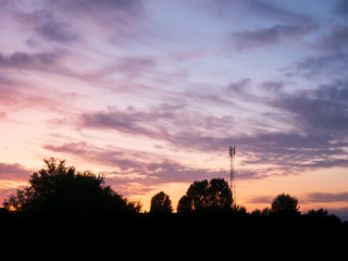 Naklejka premium view over a beautiful sunset behind a radio antenna tower.
