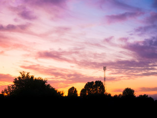 Naklejka premium view over a beautiful sunset behind a radio antenna tower.