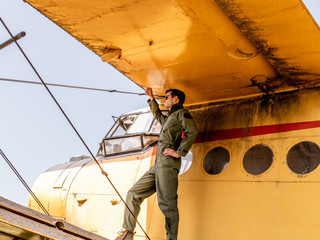 A handsome young pilot standing on the wing of a plane