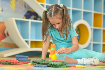 Little girl playing with colorful plastic blocks