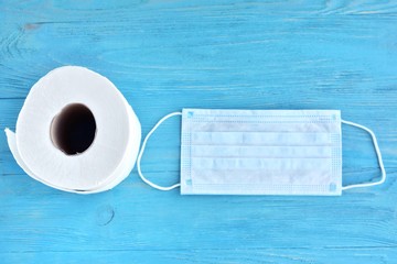 roll of toilet paper and sterile protective masks with selective focus on blue wooden background....