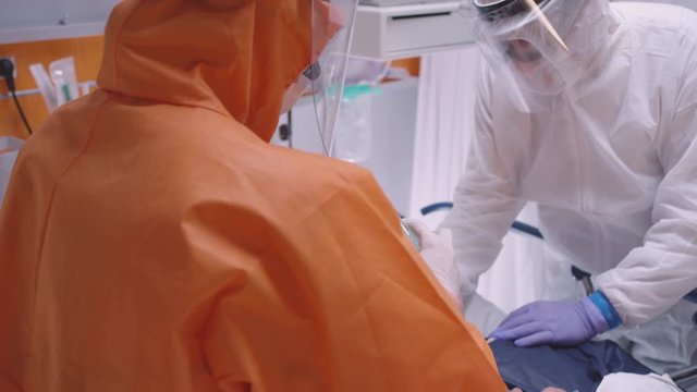 Doctor in Protective Suit Putting on Oxygen Mask on Patient Suffering from Coronavirus - Medium Tilting Shot  in Slow Motion