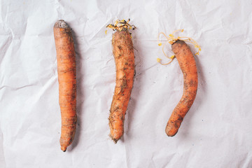 Ugly misshapen carrots on craft paper background. Concept of zero waste production. Top view. Copy...