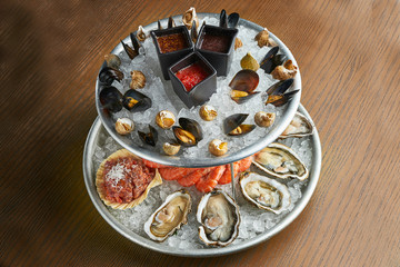 A large dish with fresh seafood on ice - oysters, shrimps, mussels, scallops. Close up. Catering