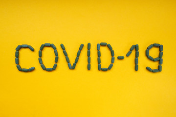 The inscription COVID-19 on yellow background. Coronavirus pandemic. The spread of corona virus in the World. COVID-19 infection concept.