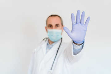 portrait of doctor wearing protective mask and gloves indoors. Making a stop sign with hand. Corona virus concept
