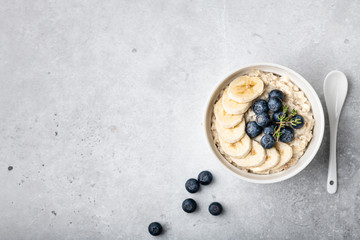oatmeal with blueberries and banana in a white bowl on a light background. Top view. Breakfast