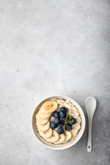 oatmeal with blueberries and banana in a white bowl on a light background. Top view. Breakfast