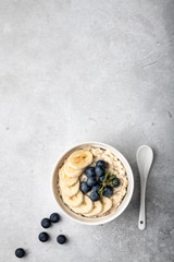 oatmeal with blueberries and banana in a white bowl on a light background. Top view. Breakfast
