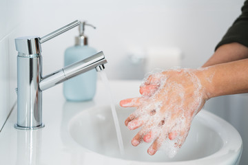Hygiene. Cleaning Hands. Washing hands with soap. Young woman washing hands with soap over sink in bathroom, closeup. Covid 19. Coronavirus.