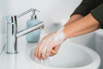 Hygiene. Cleaning Hands. Washing hands with soap. Young woman washing hands with soap over sink in...