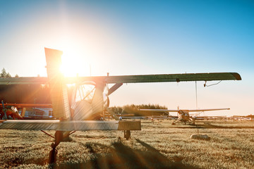 small airport landscape at sunset with vintage propeller airplane parked on grass runway against...