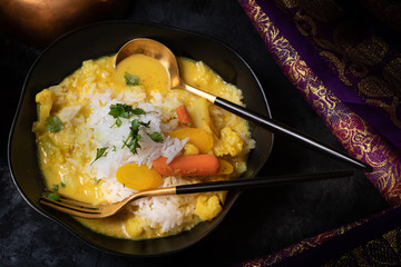 Vegan Thai red curry over rice served in traditional bowl and cuttlery
