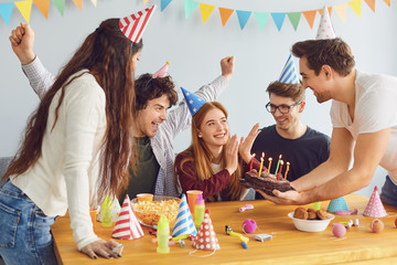Happy Birthday party. A group of friends with a cake wishes the girl a happy birthday