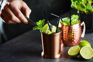 Cuba Libre, Rum and Cola drink with lime in copper mugs on a bar