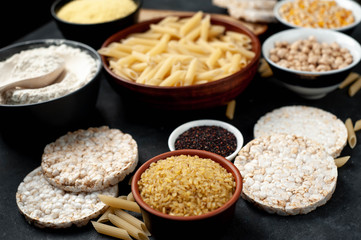 Selection of gluten free food. Chickpeas, bread, couscous, bulgur, pasta, bread, flour, quinoa on a stone background