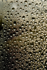 Rain drops on glasse surface on gold background. Natural Pattern of raindrops isolated on color background. Macro photo of water drops