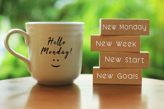 Hello Monday concept with inspirational quote on wooden blocks - New Monday. New Week, New Start. New Goals. And a smiling face on a white morning cup of coffee or tea.