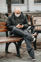 Fototapeta na wymiar Guy on street in protective masks looking at phone