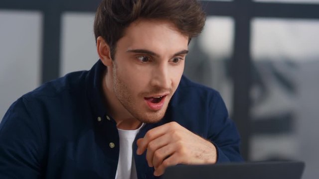 Surprised businessman getting good news letter on computer in office.
