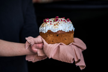 Easter delicious cake hold women's hands in napkins on a black background .