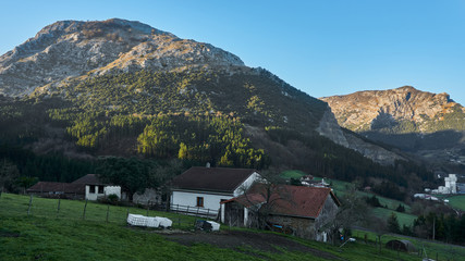 Fototapeta na wymiar Farm next to mountains at dawn Typical Basque farm next to fields Urkiola Natural Park