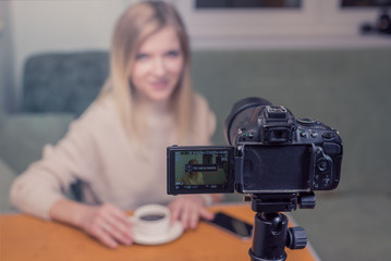 Naklejka premium Beautiful girl blogger in front of camera/ Beautiful blogger woman explains while online live streaming in front of camera. Night working influencer. Focus camera
