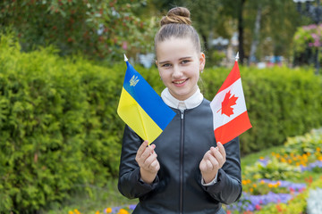 Fototapeta na wymiar Girl schoolgirl with the flags of Canada and Ukraine. Ukrainian diaspora.