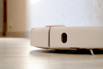 Robotic vacuum cleaner on laminate wood floor.