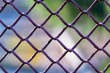 Metallic chain fence link net with blue defocused background