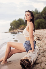 Fototapeta na wymiar beautiful young and athletic girl on the beach wearing a boho blouse and shorts, sea sunset, lifestyle and fashion