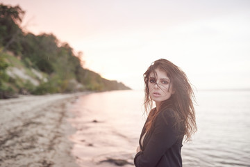 beautiful young and athletic girl on the beach dressed in a black suit, sea sunset, lifestyle and fashion