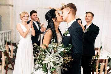 Happy newlyweds kiss after marriage ceremony