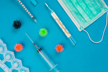Protective medical mask, thermometer, syringe and viruses on blue backgroun